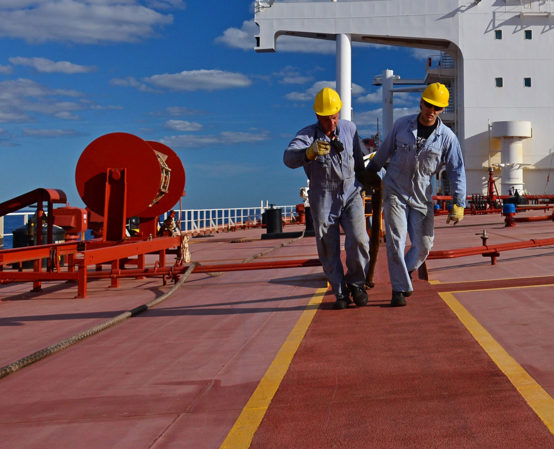 Two seafarers handling a mooring line on a tanker deck at sea