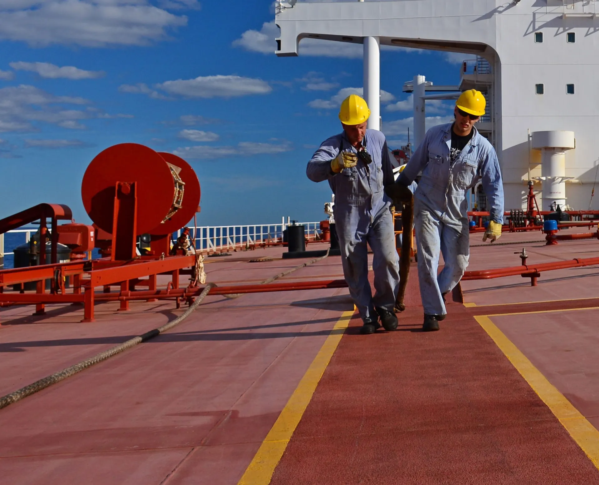 Two seafarers handling a mooring line on a tanker deck at sea